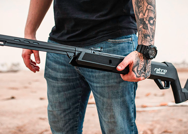 Foto de um homem com o braço tatuado segurando uma carabina de pressão Nitro Force